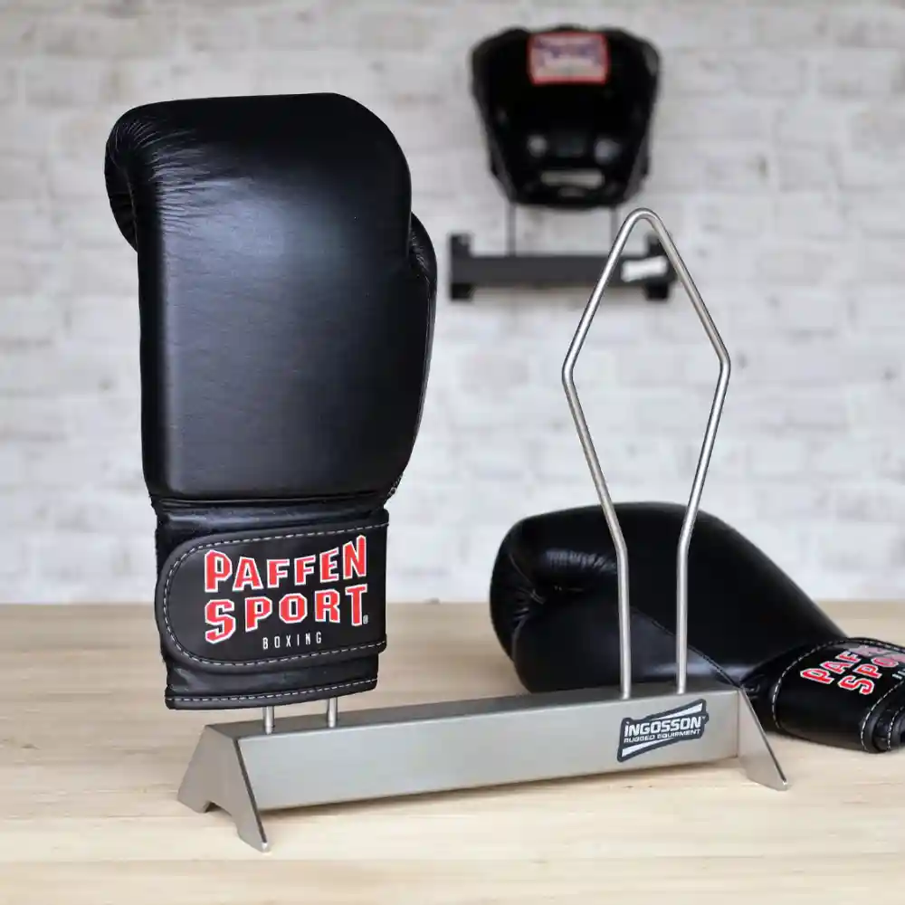 Black boxing gloves on a Ingosson stainless rack on awooden surface